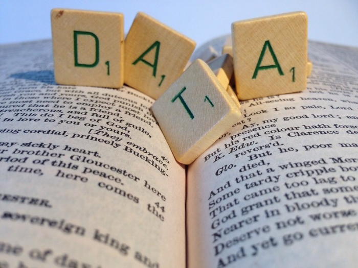 Bilde av åpen bok med spillbrikker oppå som staver "data"